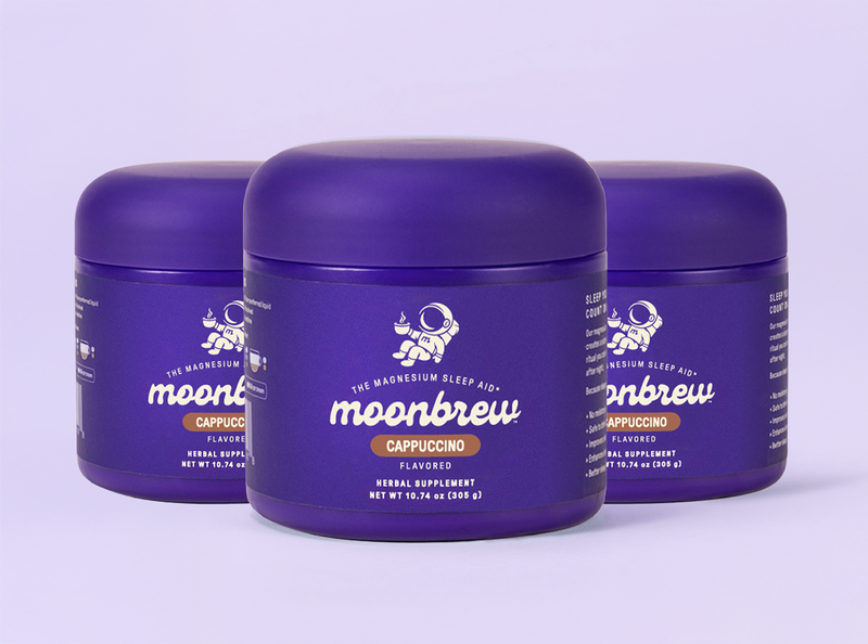 Three-quarter front view of three MoonBrew Cappuccino tubs showing purple label, and 10.74 oz net weight on a lavender background
