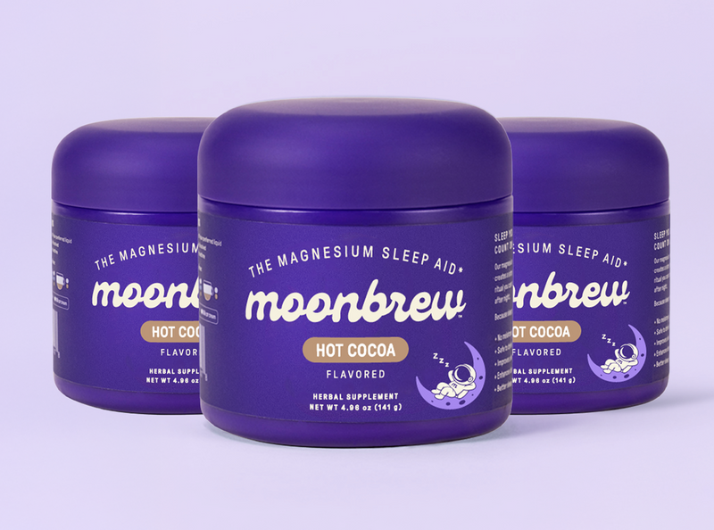 Front view of three Moonbrew Hot Cocoa jars labeled The Magnesium Sleep Aid on a pale purple background