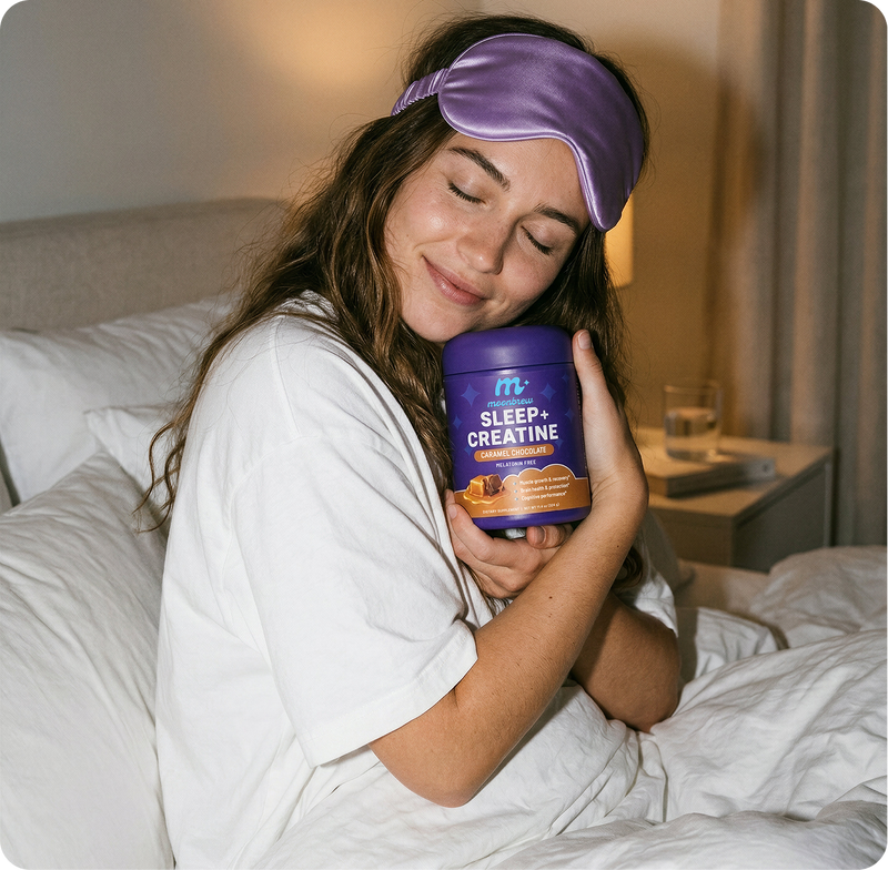 Woman hugging a MoonBrew Sleep and Creatine caramel chocolate jar in bed, wearing a purple sleep mask and smiling