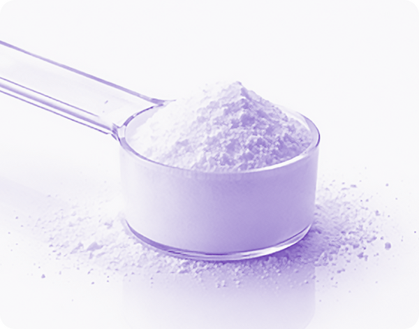 Close-up side view of a scoop of white creatine monohydrate powder on a reflective white surface