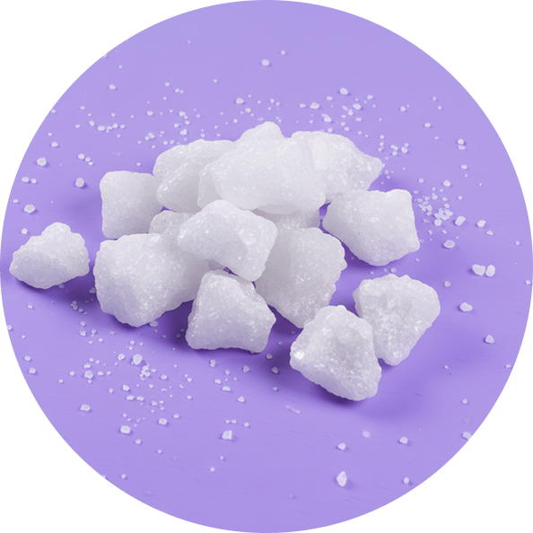 Top view of white magnesium crystal chunks showing coarse, granular texture on a purple circular background