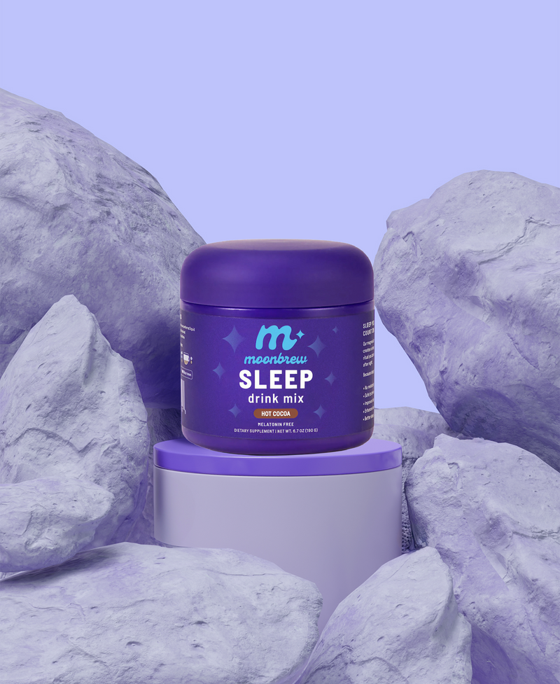 Front view of MoonBrew SLEEP drink mix jar (Hot Cocoa flavor) with light purple rocks in the background