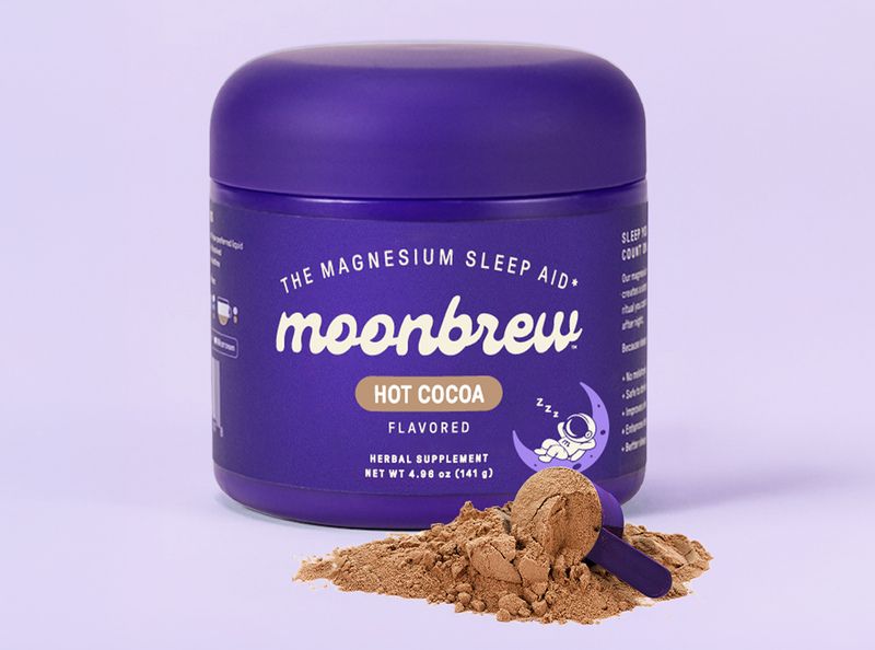 Front of MoonBrew Homestyle Hot Cocoa tub with purple label Magnesium Sleep Aid and cocoa powder scoop on purple background