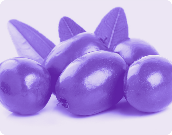 Close-up of jujube fruits and leaves showcasing glossy skins on a pale background