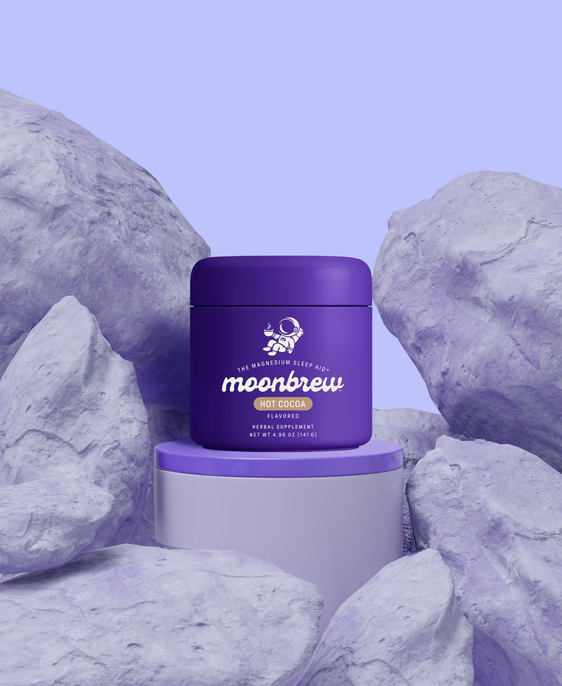 Front view of MoonBrew Hot Cocoa jar showcasing purple packaging and moonbrew label on a lavender rock backdrop